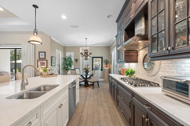 kitchen featuring hardwood / wood-style flooring, decorative light fixtures, appliances with stainless steel finishes, sink, and dark brown cabinetry