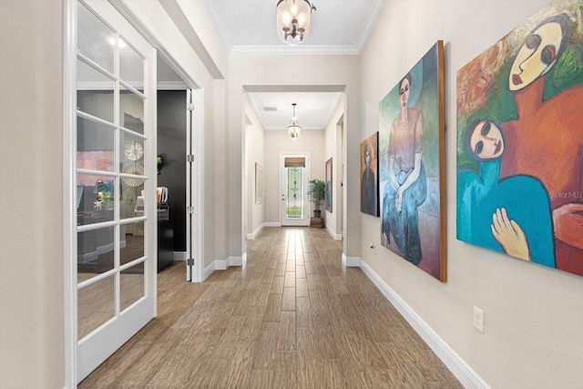 hallway featuring french doors, wood-type flooring, an inviting chandelier, and ornamental molding