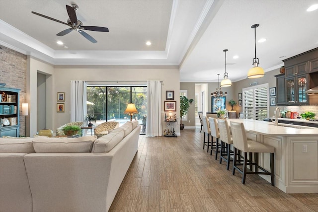 living room featuring ceiling fan, ornamental molding, a tray ceiling, and dark hardwood / wood-style flooring