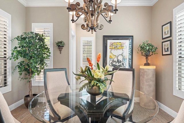 dining space featuring a healthy amount of sunlight, wood-type flooring, an inviting chandelier, and ornamental molding