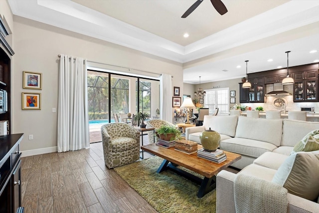 living room with ceiling fan, dark hardwood / wood-style floors, and a tray ceiling