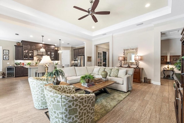 living room with light hardwood / wood-style flooring, ceiling fan, ornamental molding, and beverage cooler