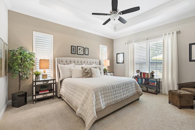 bedroom featuring ceiling fan, light colored carpet, a raised ceiling, and crown molding