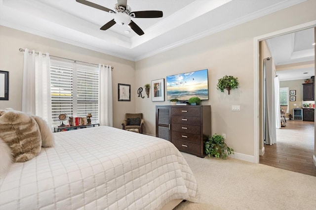 bedroom with a tray ceiling, ceiling fan, light hardwood / wood-style floors, and crown molding