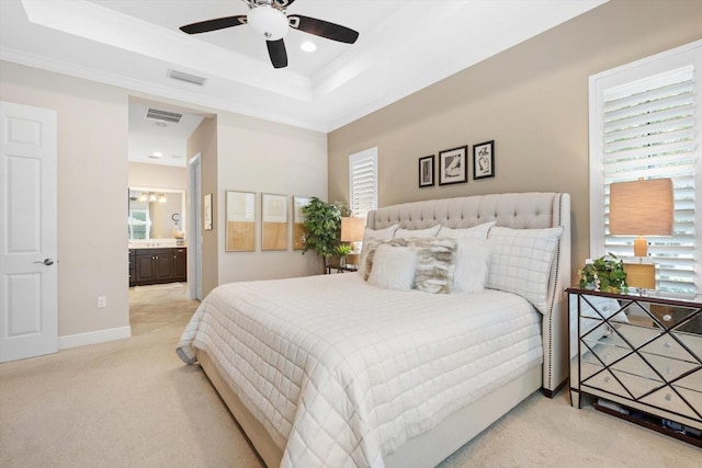 bedroom featuring multiple windows, ceiling fan, light carpet, and ensuite bath