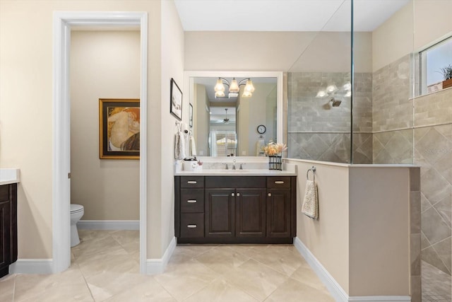 bathroom featuring tiled shower, toilet, and vanity