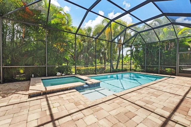 view of pool with a patio area, glass enclosure, and an in ground hot tub