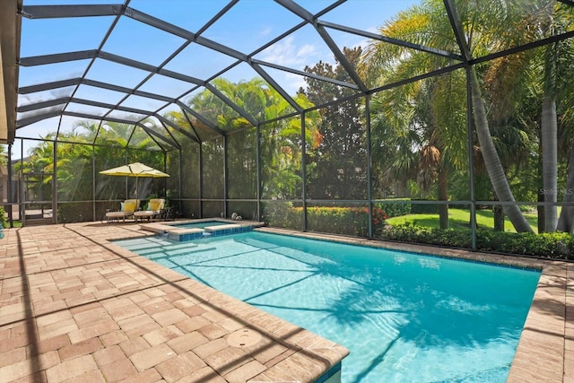 view of pool with glass enclosure, a patio area, and an in ground hot tub