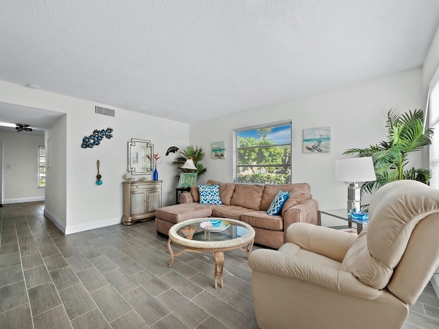 living room featuring a textured ceiling, visible vents, and baseboards