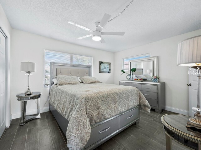 bedroom with a ceiling fan, wood finish floors, a textured ceiling, and baseboards