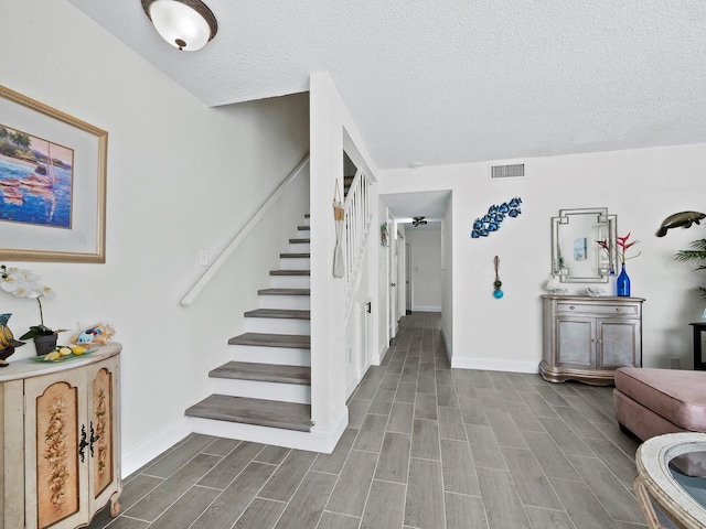 interior space with wood tiled floor, stairs, visible vents, and baseboards