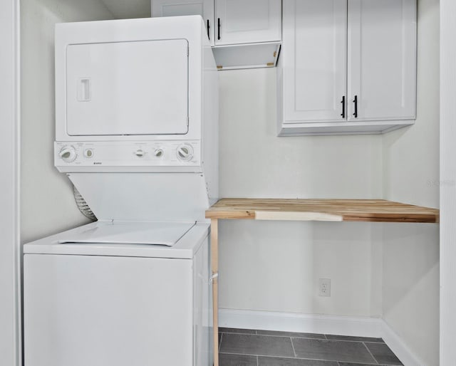 clothes washing area featuring stacked washer / dryer, laundry area, and baseboards