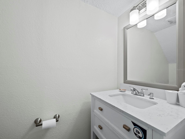 bathroom featuring a textured wall, vanity, and a textured ceiling