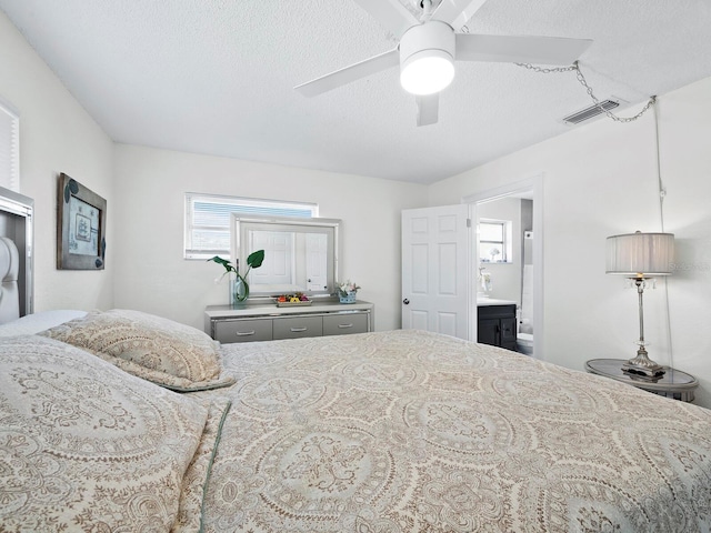 bedroom with a ceiling fan, connected bathroom, visible vents, and a textured ceiling