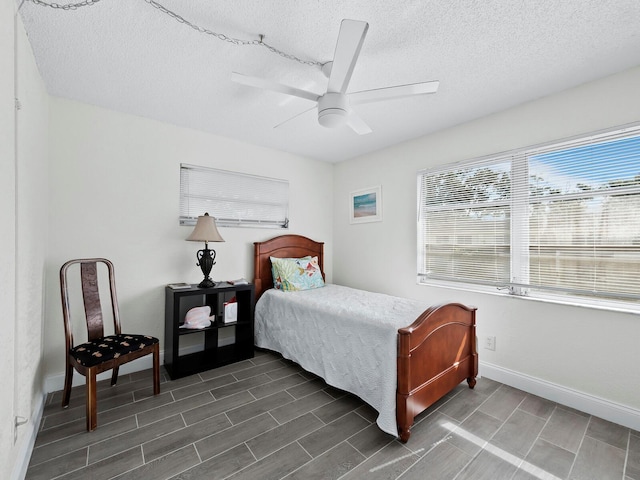 bedroom featuring a textured ceiling, wood tiled floor, a ceiling fan, and baseboards