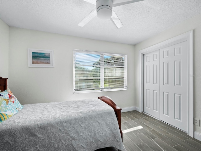 bedroom with ceiling fan, a textured ceiling, wood finish floors, baseboards, and a closet