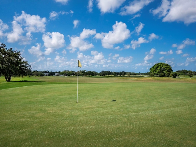 view of property's community featuring view of golf course and a lawn