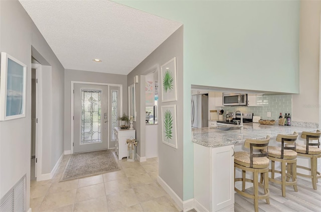 tiled entrance foyer with a textured ceiling and sink