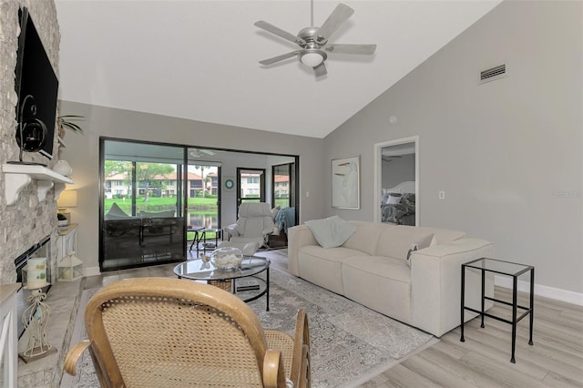 living room with high vaulted ceiling, ceiling fan, light wood-type flooring, and a fireplace