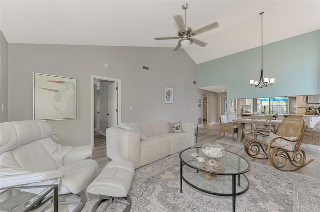 living room featuring light wood-type flooring, ceiling fan with notable chandelier, and high vaulted ceiling