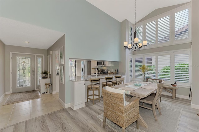 dining area with high vaulted ceiling, a chandelier, and light hardwood / wood-style floors