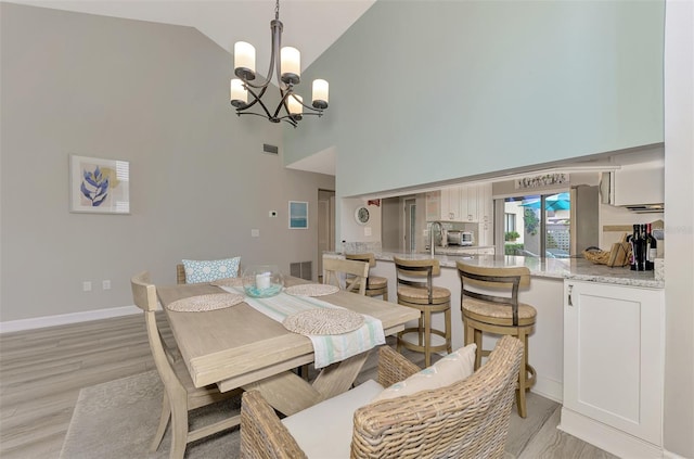 dining area featuring high vaulted ceiling, an inviting chandelier, and light wood-type flooring