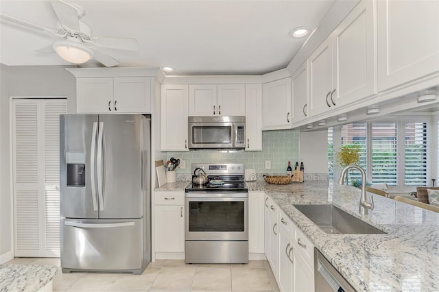 kitchen featuring white cabinetry, stainless steel appliances, sink, ceiling fan, and decorative backsplash