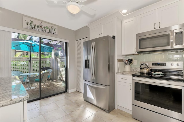 kitchen featuring light tile patterned floors, light stone countertops, ceiling fan, appliances with stainless steel finishes, and white cabinets