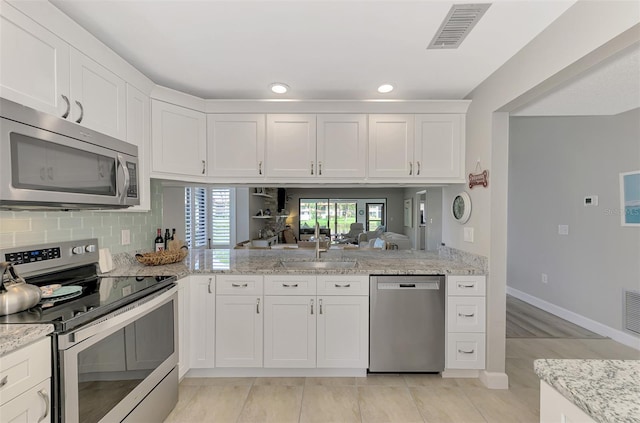 kitchen with stainless steel appliances, sink, kitchen peninsula, and white cabinetry