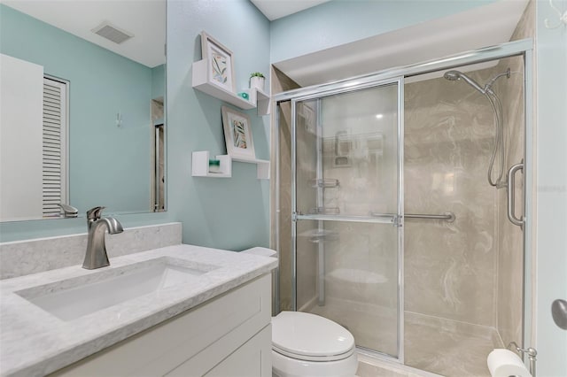 bathroom with a shower with shower door, toilet, and vanity