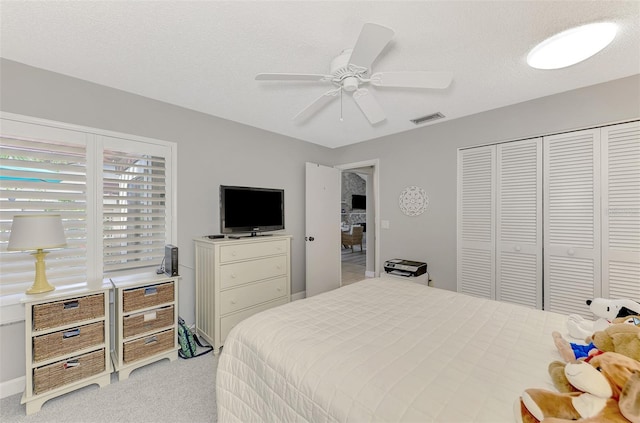 bedroom with a textured ceiling, light colored carpet, ceiling fan, and a closet