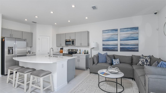 kitchen featuring stainless steel appliances, a sink, open floor plan, light countertops, and an island with sink