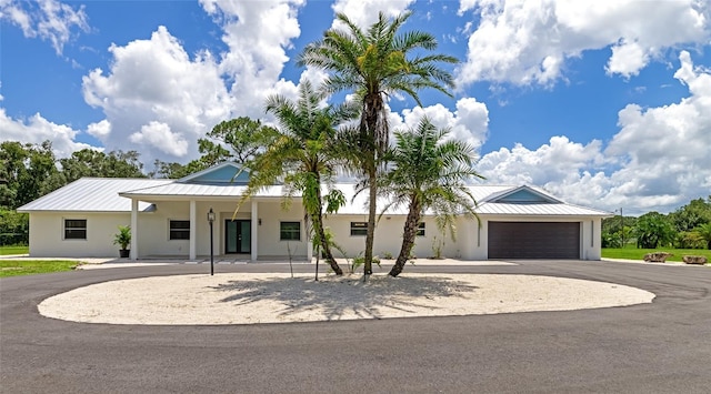 view of front of home with a standing seam roof, an attached garage, driveway, and stucco siding