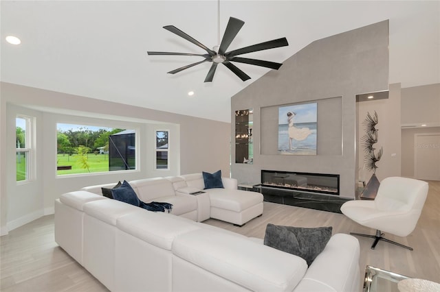 living room featuring light wood-type flooring, a large fireplace, ceiling fan, and high vaulted ceiling