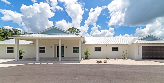 view of front of house with an attached garage, metal roof, and stucco siding