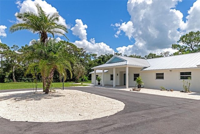 view of front of house featuring stucco siding, metal roof, and aphalt driveway