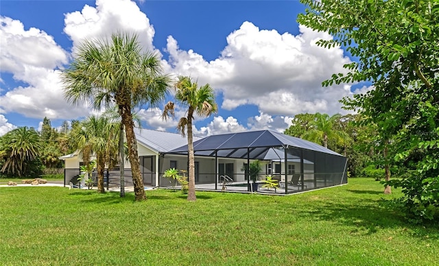 rear view of property featuring a lanai, a yard, and metal roof