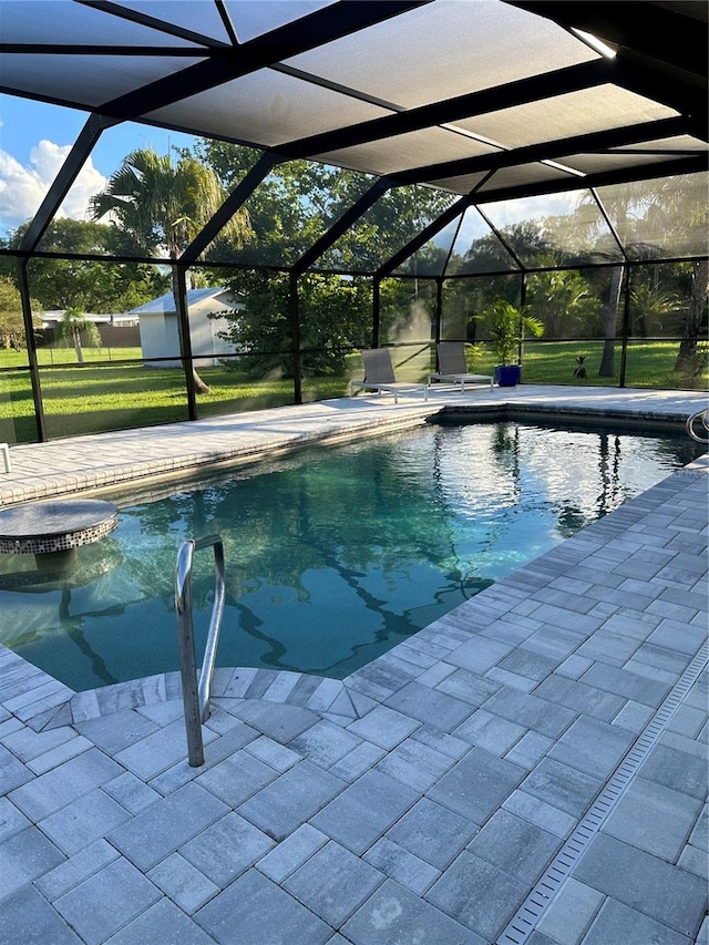 outdoor pool featuring a yard, glass enclosure, and a patio