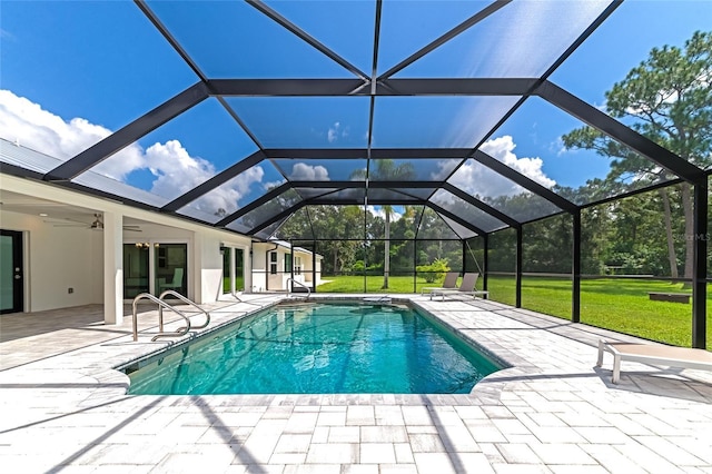 outdoor pool featuring glass enclosure, a patio, a lawn, and ceiling fan