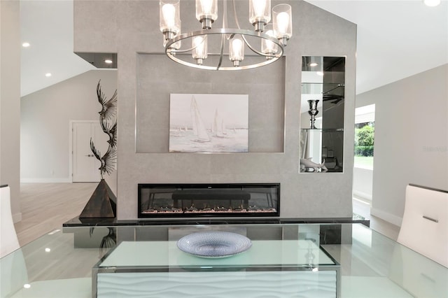 interior space featuring a chandelier, a glass covered fireplace, and lofted ceiling