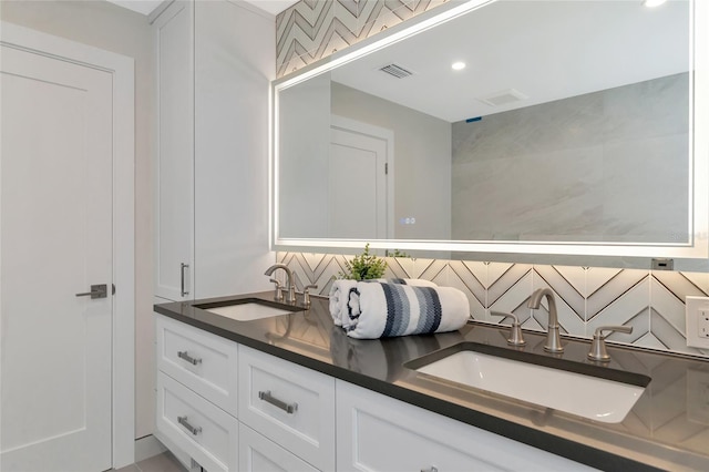 bathroom with a sink, visible vents, backsplash, and double vanity