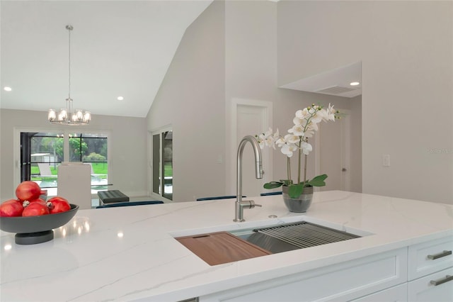 kitchen featuring light stone countertops, recessed lighting, a sink, decorative light fixtures, and a chandelier