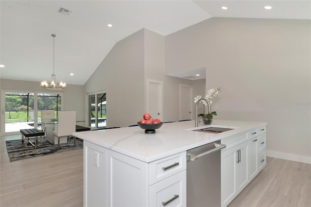 kitchen with light wood finished floors, light stone countertops, stainless steel dishwasher, white cabinets, and a sink