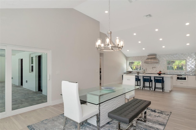 dining room with light wood finished floors, visible vents, recessed lighting, and high vaulted ceiling