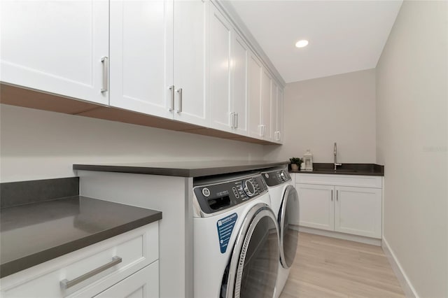 clothes washing area with light wood-style flooring, a sink, recessed lighting, cabinet space, and separate washer and dryer