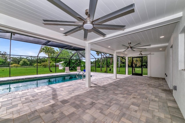 outdoor pool with a yard, glass enclosure, a ceiling fan, and a patio area