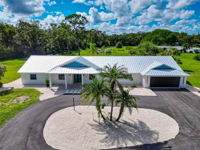 view of front of property with stucco siding, driveway, metal roof, and a front lawn