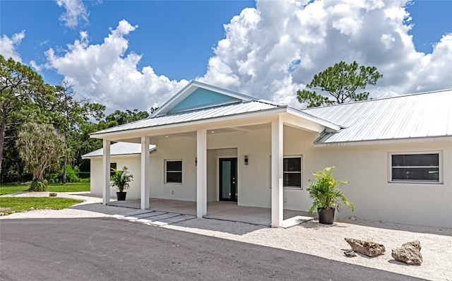 view of front of home featuring stucco siding, a patio, and metal roof