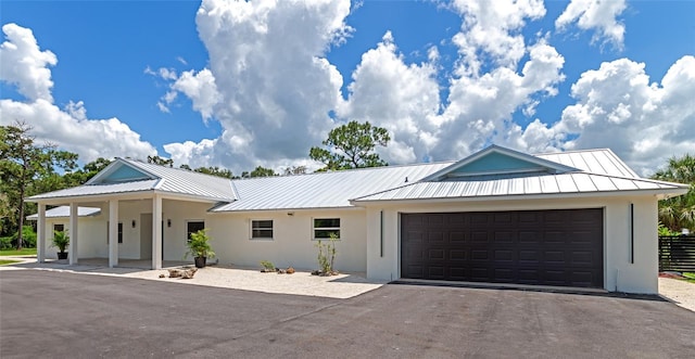 view of front of house with stucco siding, driveway, a standing seam roof, metal roof, and a garage