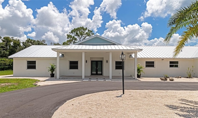 view of front of home featuring a standing seam roof, metal roof, french doors, and stucco siding